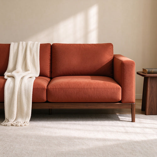 Nomad sofa with a cream knit throw, straight-on studio view
